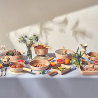 Lifestyle dining scene with FIKA Objet cookware collection arranged for multi-dish meal