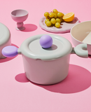 Top-down view of casserole on pink background with matching dishware – playful and compact table setting